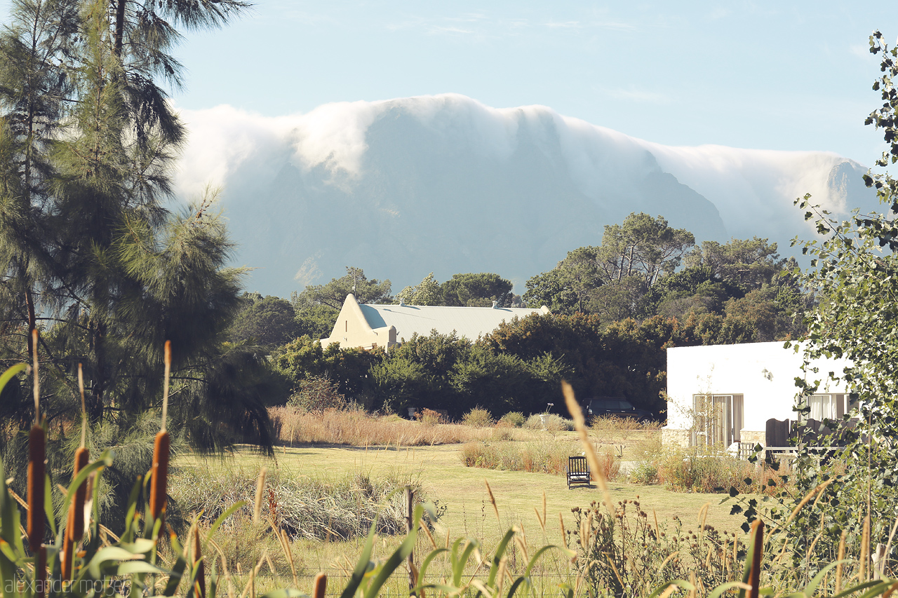 Foto von Misty clouds caress the mountains over serene Franschhoek, South Africa, where rustic charm meets natural beauty.