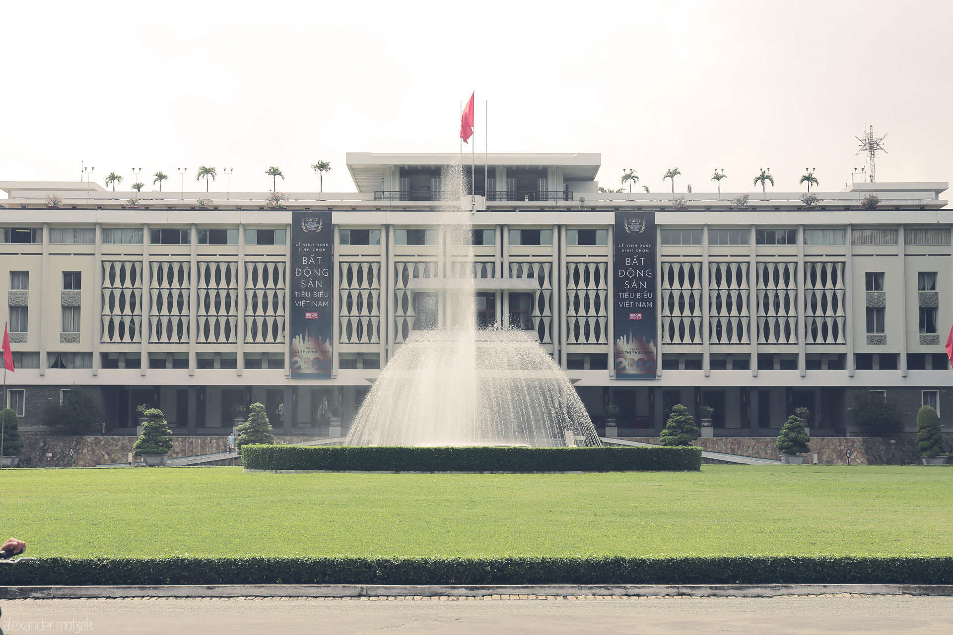 Foto von The iconic Reunification Palace stands tall amid lush Saigon gardens, its fountain glittering in Vietnam’s midday sun.