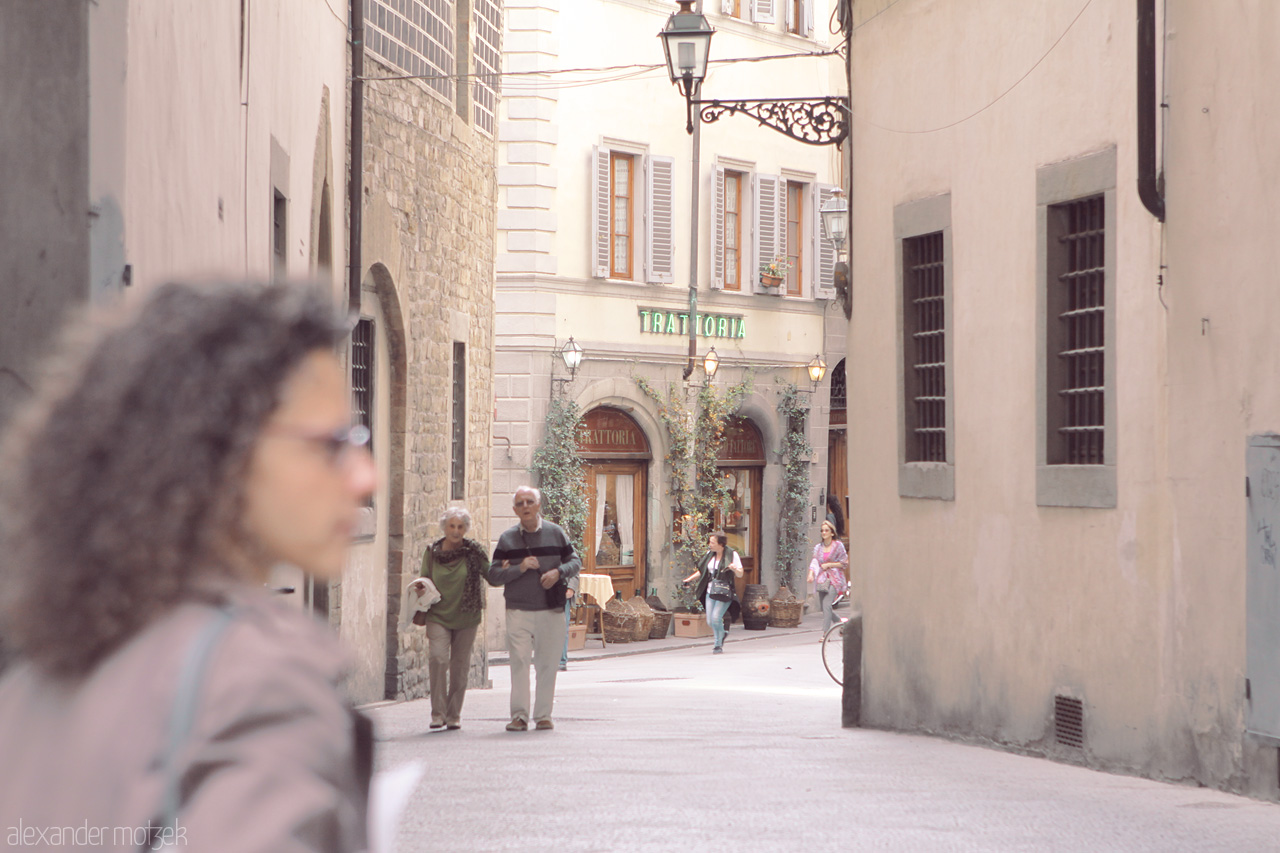 Foto von A peaceful alley in Tuscany, Italy, captures everyday life near a quaint trattoria. The rustic charm of stone buildings enchants the scene.