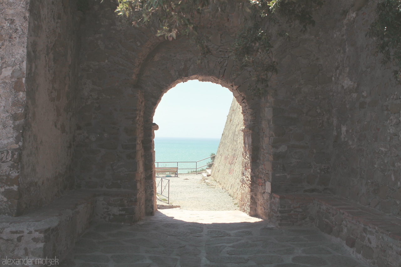 Foto von A sunlit archway invites you to the tranquil Mediterranean, capturing Tuscany's timeless allure.