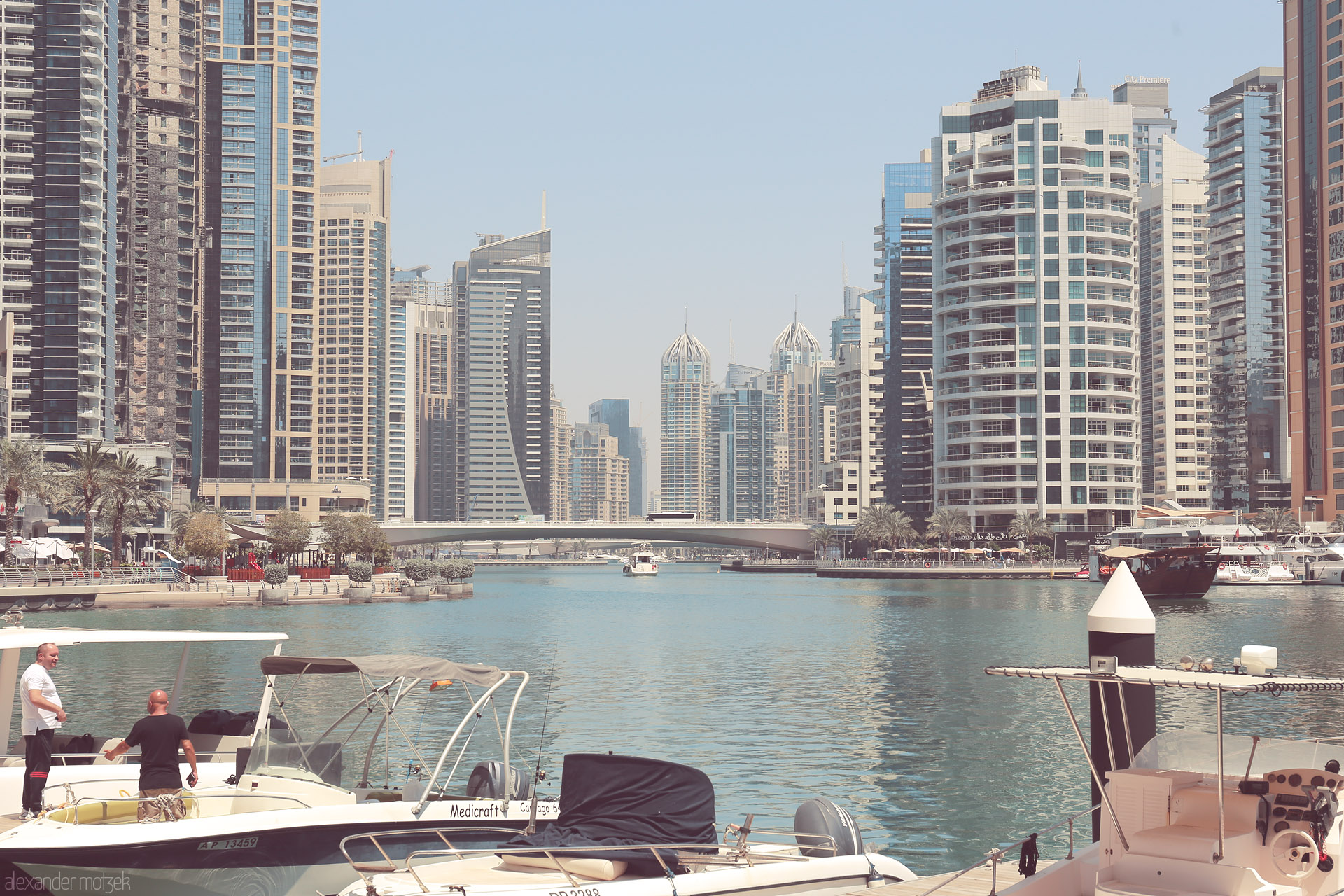 Foto von Sun-dappled yachts drift in Dubai Marina, framed by glimmering towers and modern Arabesque architecture. City life meets tranquil waters.