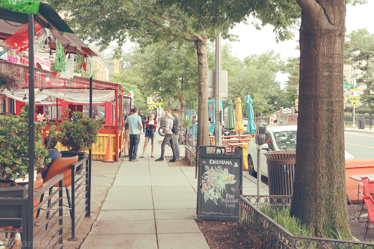 Foto von A vibrant sidewalk in Washington, D.C. showcases al fresco dining, lively foliage, and a hint of urban charm, capturing the city's bustling spirit.