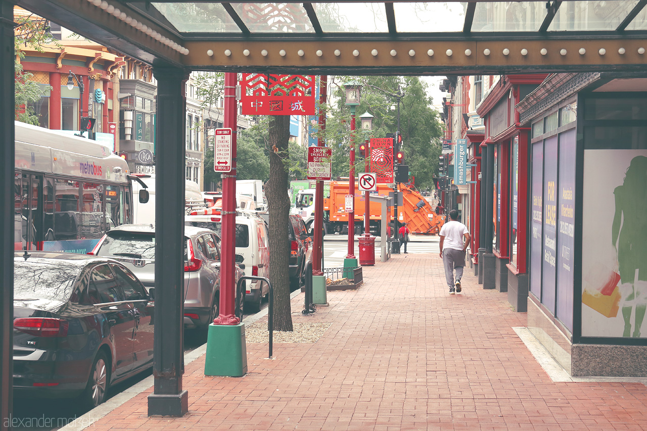 Foto von Bustling streets of DC's Chinatown, where urban life meets cultural charm under vibrant signs and lined walkways.