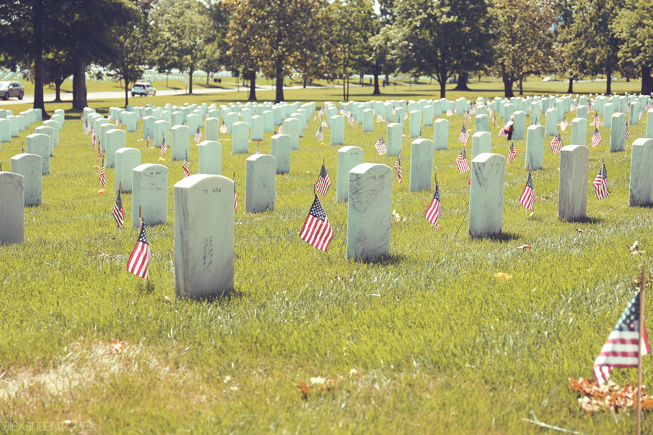 Foto von Rows of gravestones with American flags at Arlington National Cemetery, reflecting a solemn tribute.