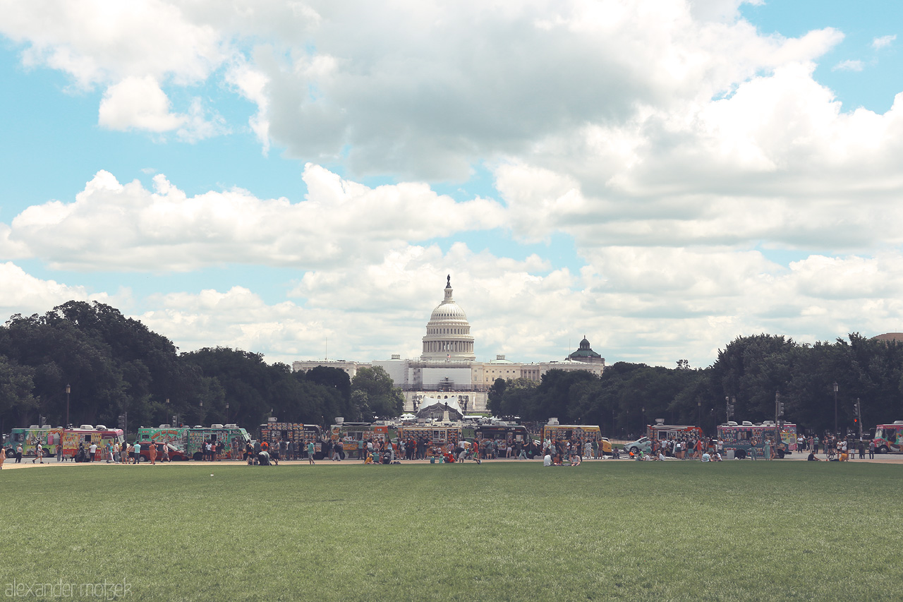 Foto von The U.S. Capitol stands majestically under a wide sky, framed by the lush National Mall and flanked by vibrant stalls in Washington, D.C.