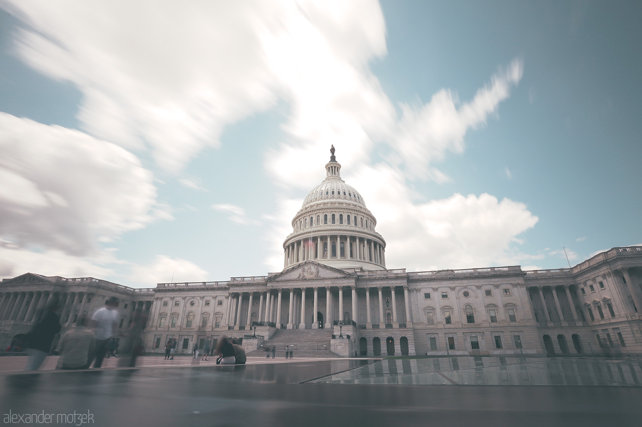 Foto von The iconic dome of the U.S. Capitol in Washington D.C. under a daylit sky, capturing its timeless grandeur and bustling foreground.