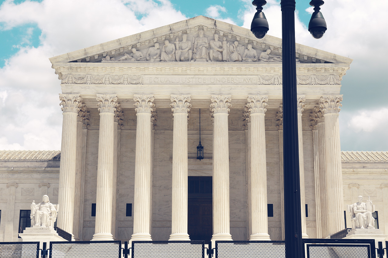 Foto von The iconic façade of the U.S. Supreme Court in Washington, D.C., showcasing its grand marble columns under a bright sky.